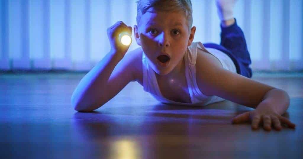 boy with flashlight looking under bed